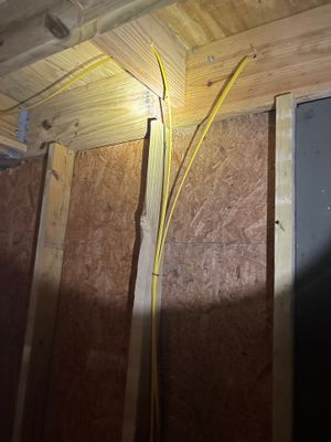 Interior crawl space or basement with yellow PVC drainage pipe being installed along the foundation perimeter, showing