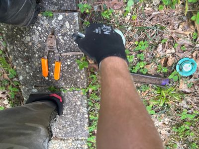 An overhead view of yard drainage work in progress showing a person installing or inspecting drainage components in