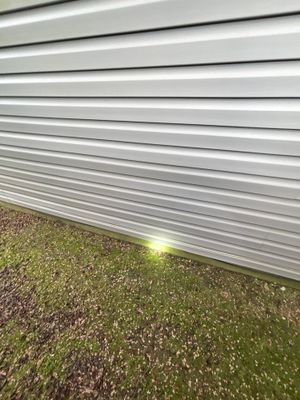 An installed exterior drainage system with a low-voltage landscape light visible along the foundation perimeter where