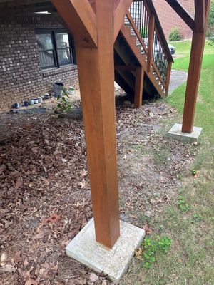 A wooden support post installed on a concrete pad beneath a deck structure, showing active foundation support work in