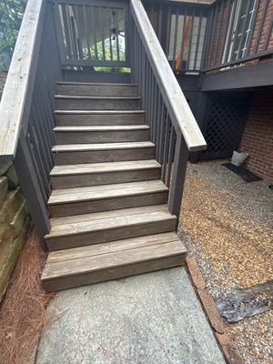 Exterior wooden deck stairs and landing with concrete pad below, showing the structure before any foundation or