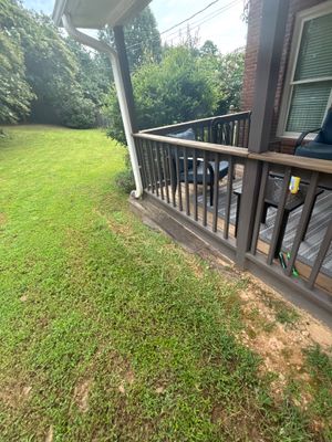 A residential backyard with a deck and manicured lawn showing no visible foundation repair work, drainage