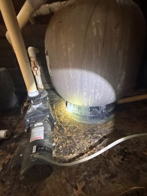 An interior sump pump basin is visible with water and sediment, showing active installation or operation of a basement