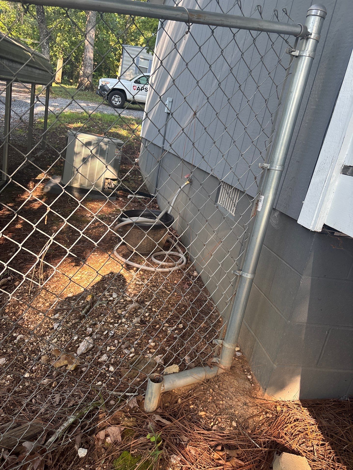 Exterior yard drainage installation with a catch basin and drainage pipe visible along the foundation perimeter during