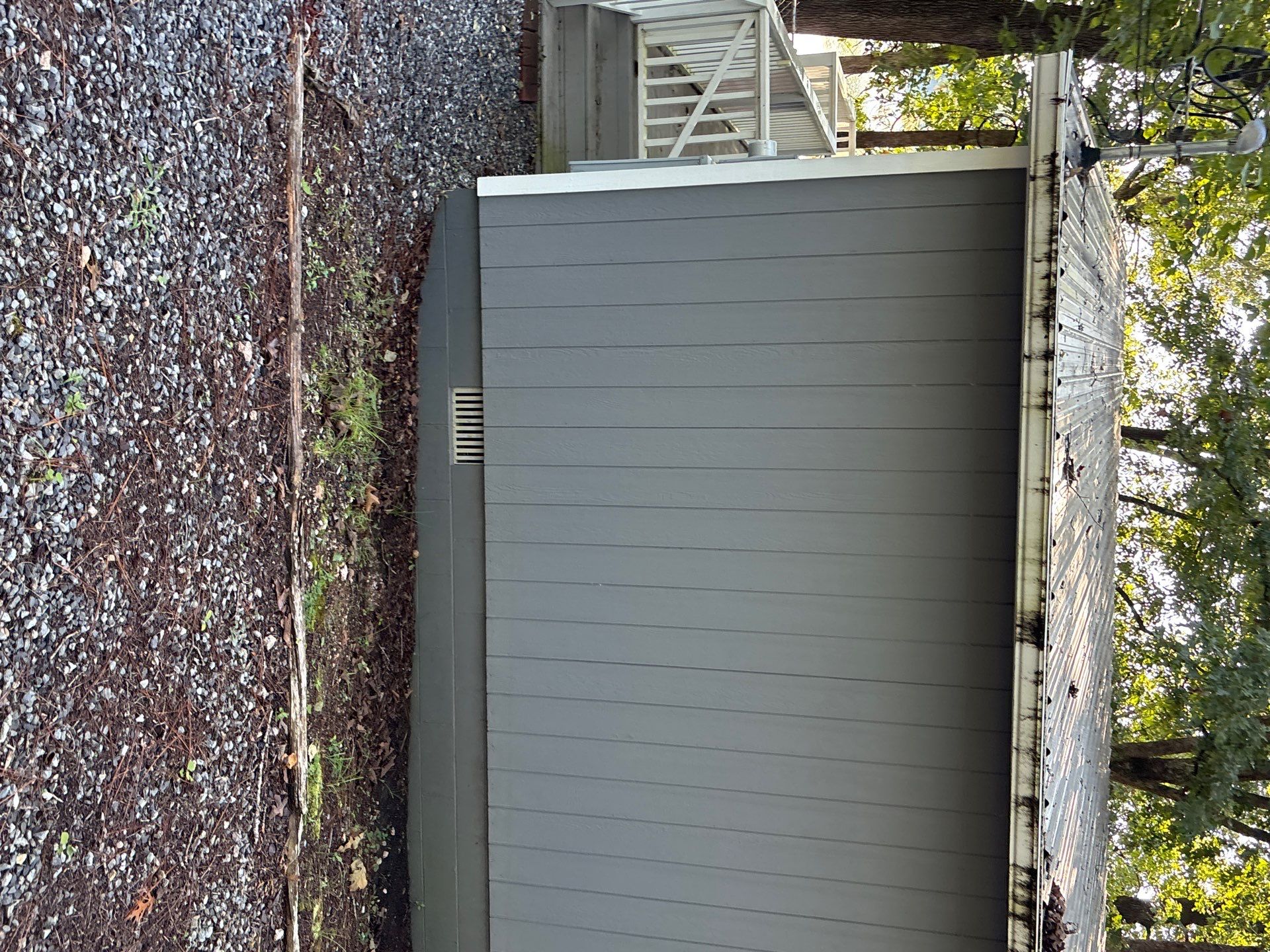 A modern gray composite fence panel installed between brick walls in a completed residential exterior