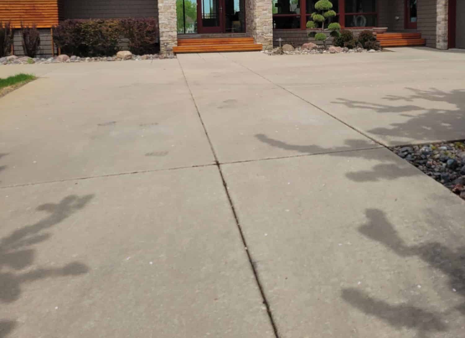 Before: weathered and stained concrete driveway slabs in front of an Alabama home