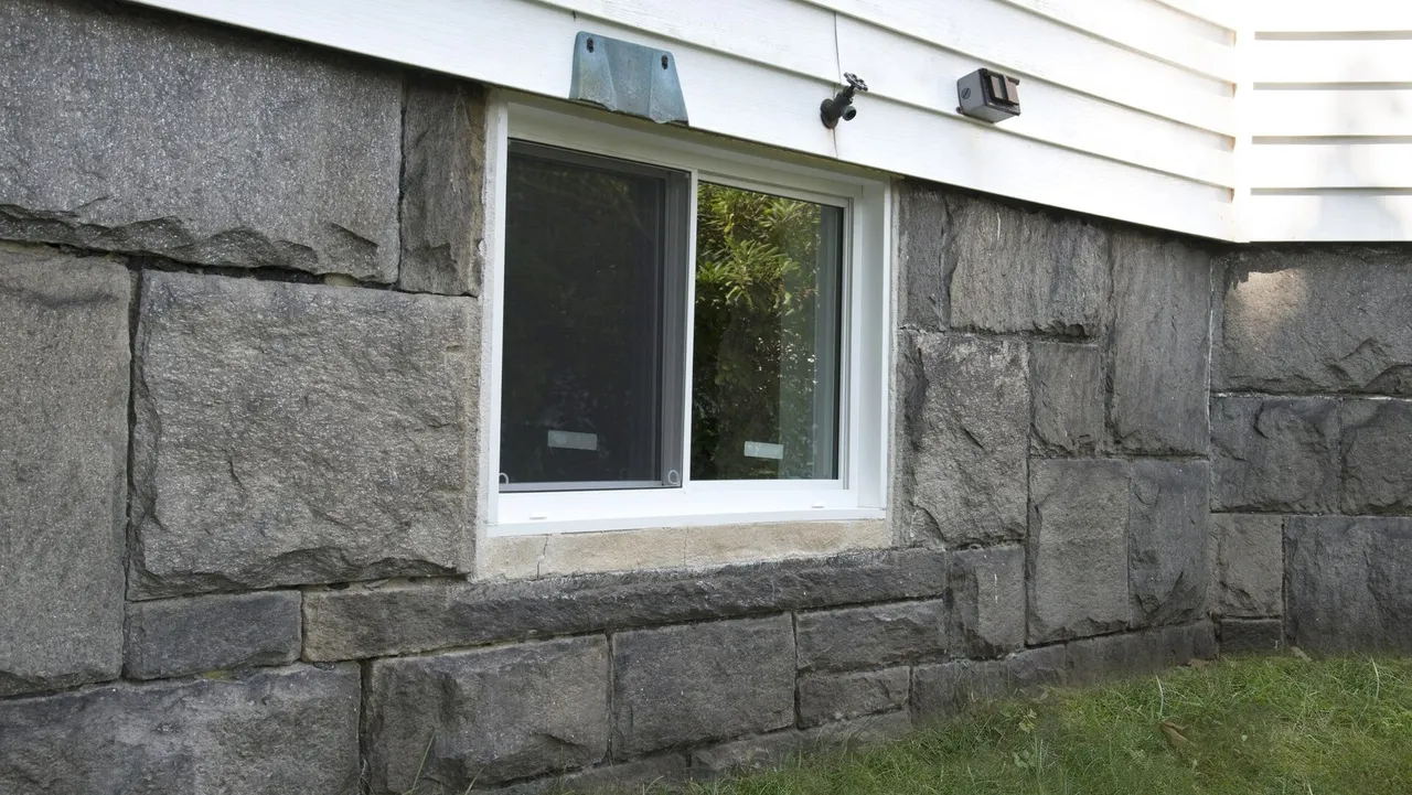 APS Foundation Repair and Waterproofing inspecting stone basement foundation for cracks and mortar deterioration.