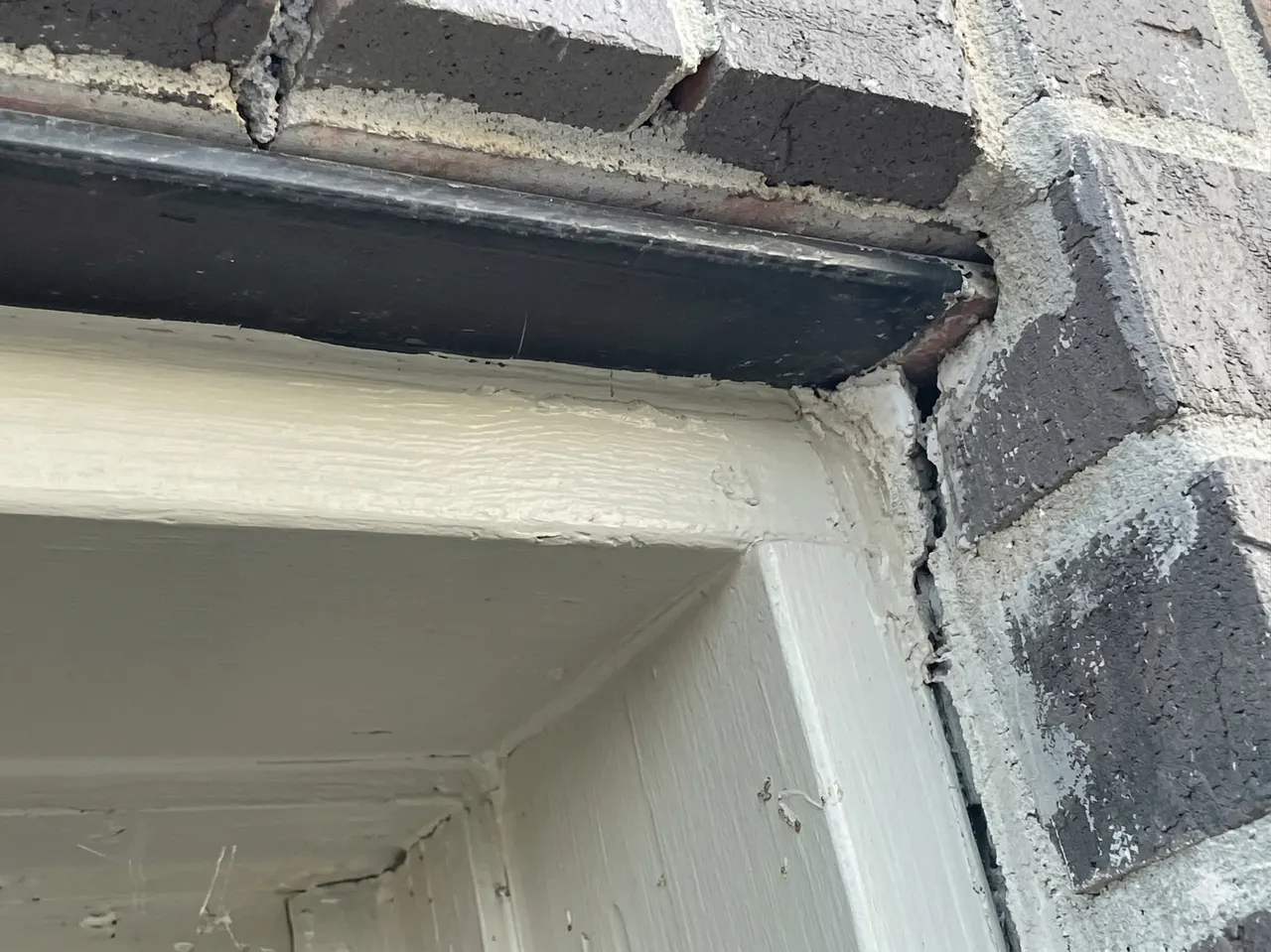 APS Foundation Repair and Waterproofing inspecting damaged brick and mortar around an exterior door frame.
