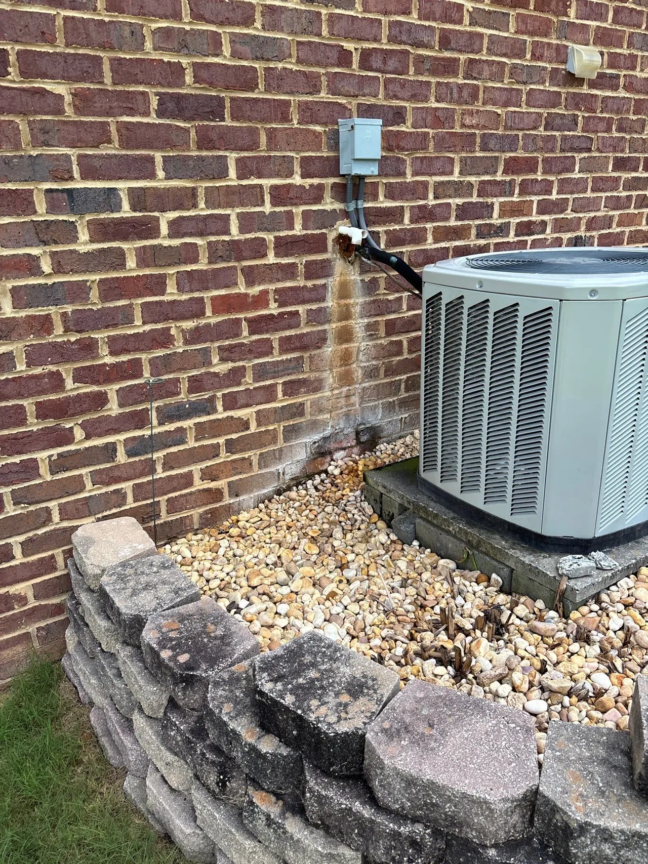 APS Foundation Repair and Waterproofing inspecting exterior brick wall with water staining, efflorescence, and vertical