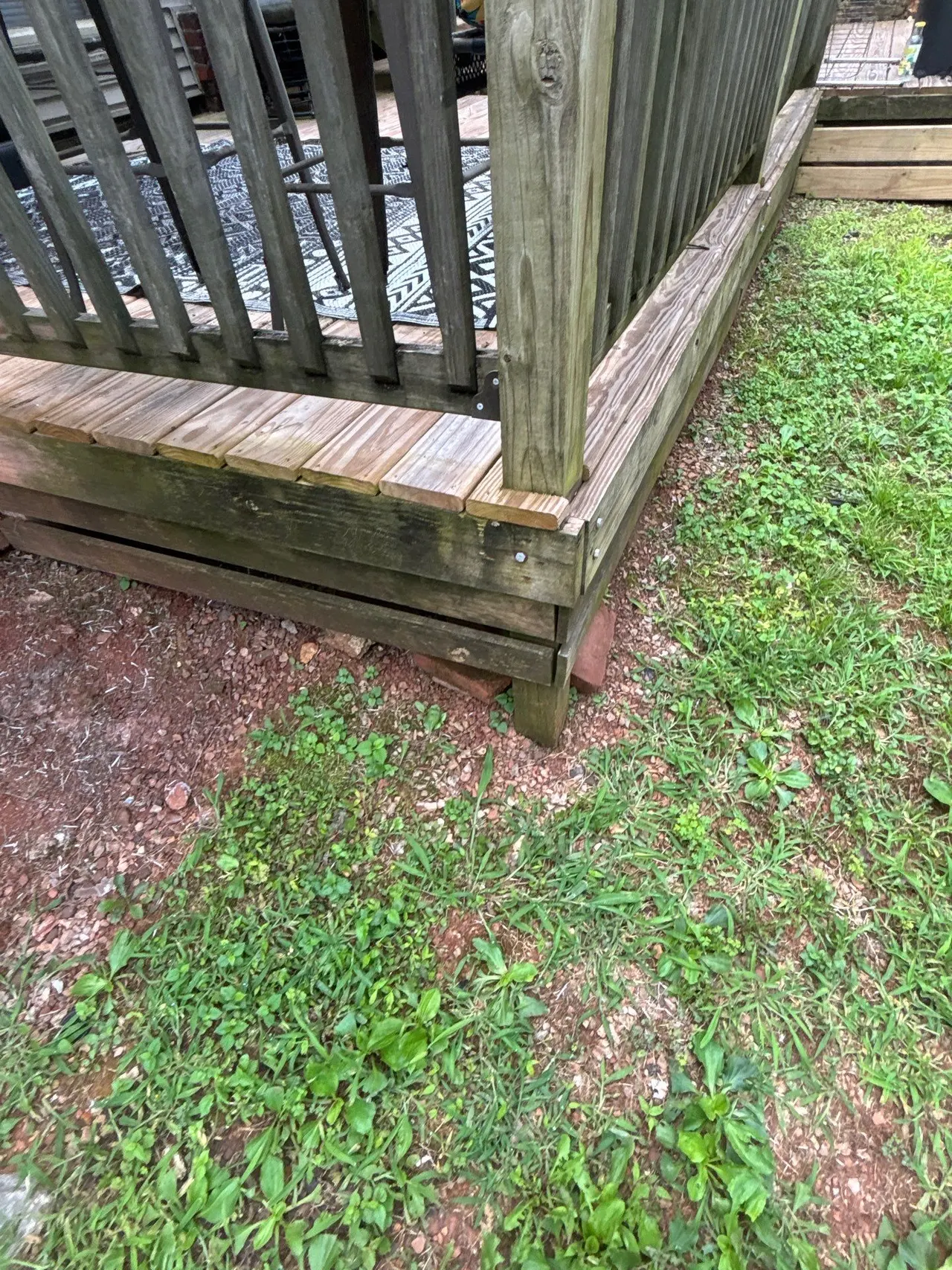 APS Foundation Repair and Waterproofing inspecting uneven deck support and makeshift brick shims in Birmingham, AL.