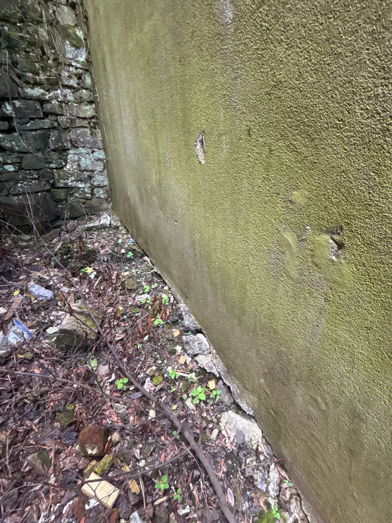 APS Foundation Repair and Waterproofing inspecting a bowing exterior foundation wall with cracks and an adjacent stone block