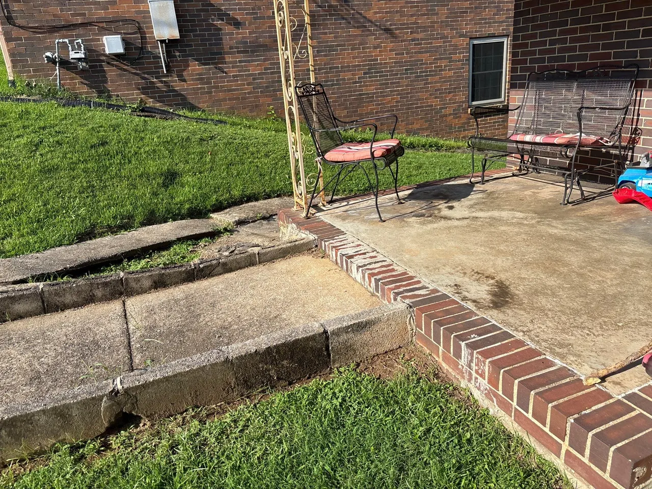 APS Foundation Repair and Waterproofing inspecting sunken concrete steps and cracked walkway at a residential exterior
