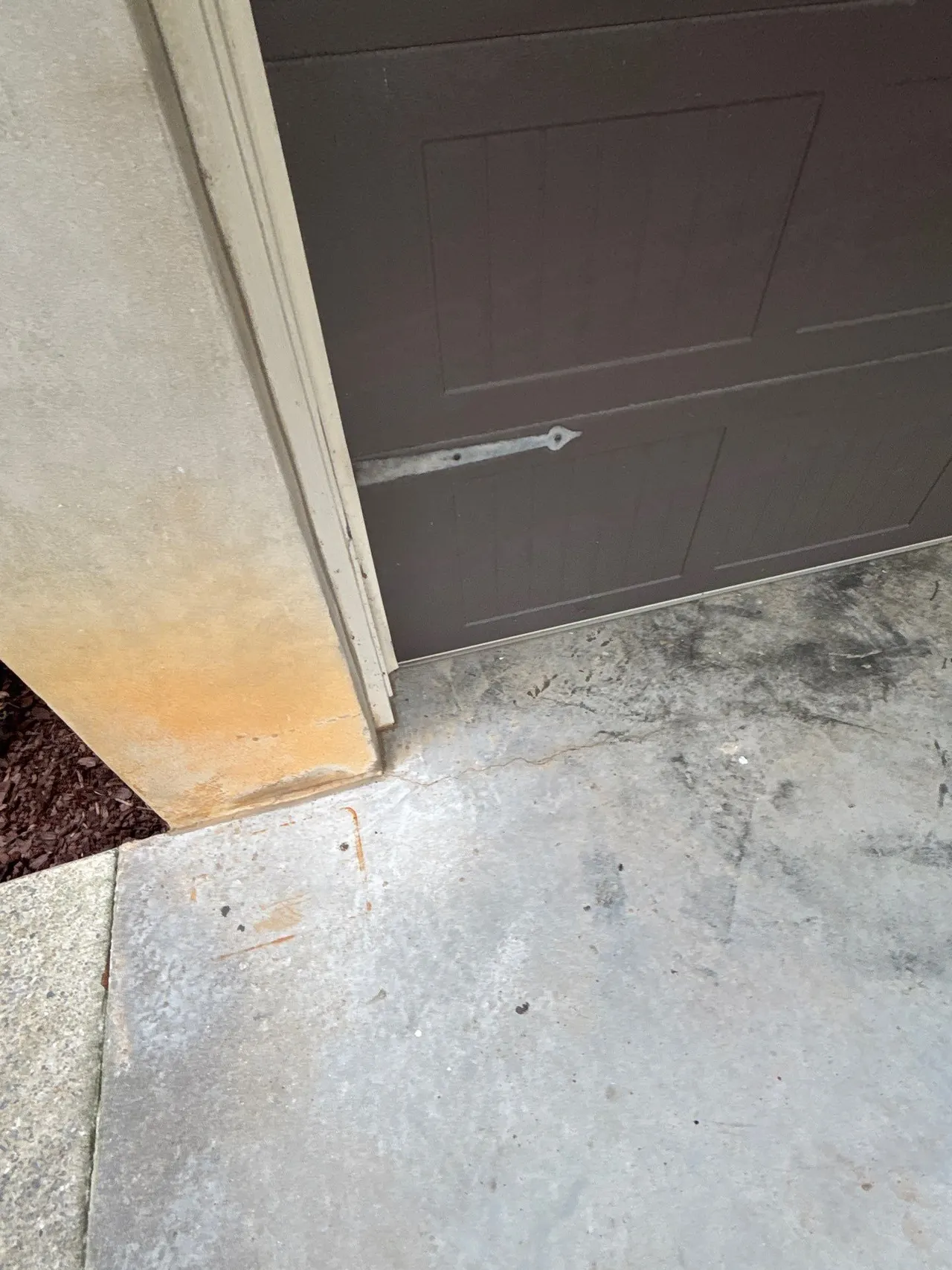 APS Foundation Repair and Waterproofing inspecting concrete cracks in a residential driveway near a garage entrance