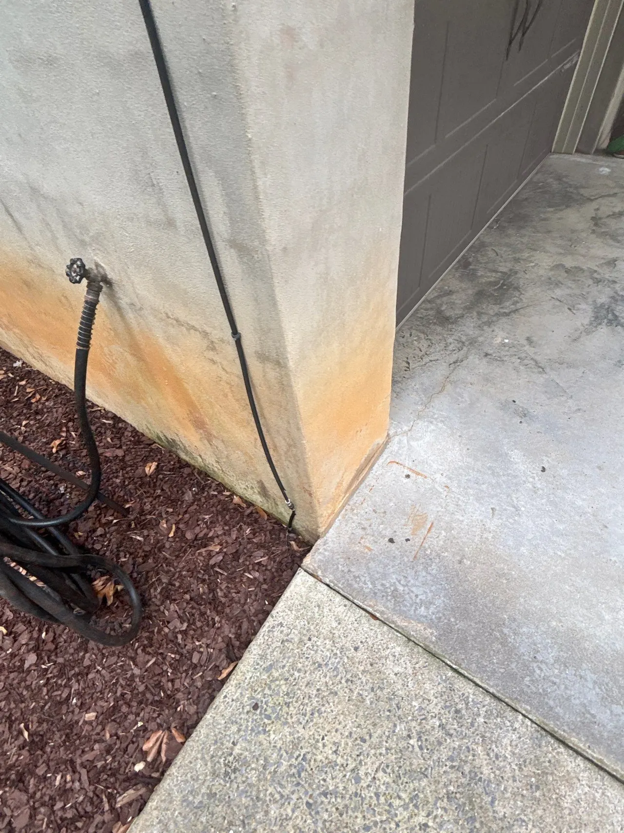 APS Foundation Repair and Waterproofing inspecting water stains and cracked concrete on a residential exterior foundation