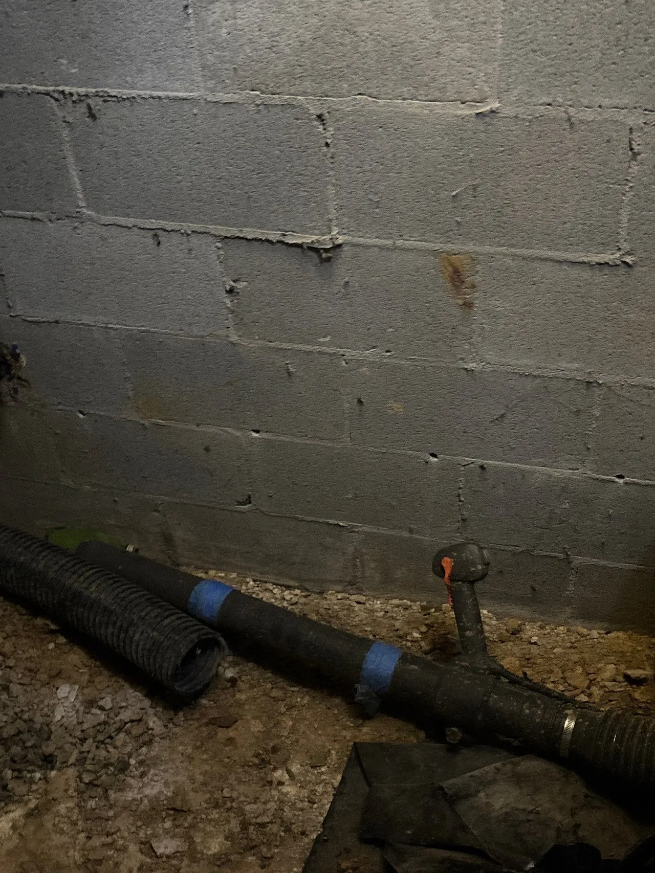 APS Foundation Repair and Waterproofing inspecting basement block foundation wall stains and drainage pipes in Sterrett, AL.