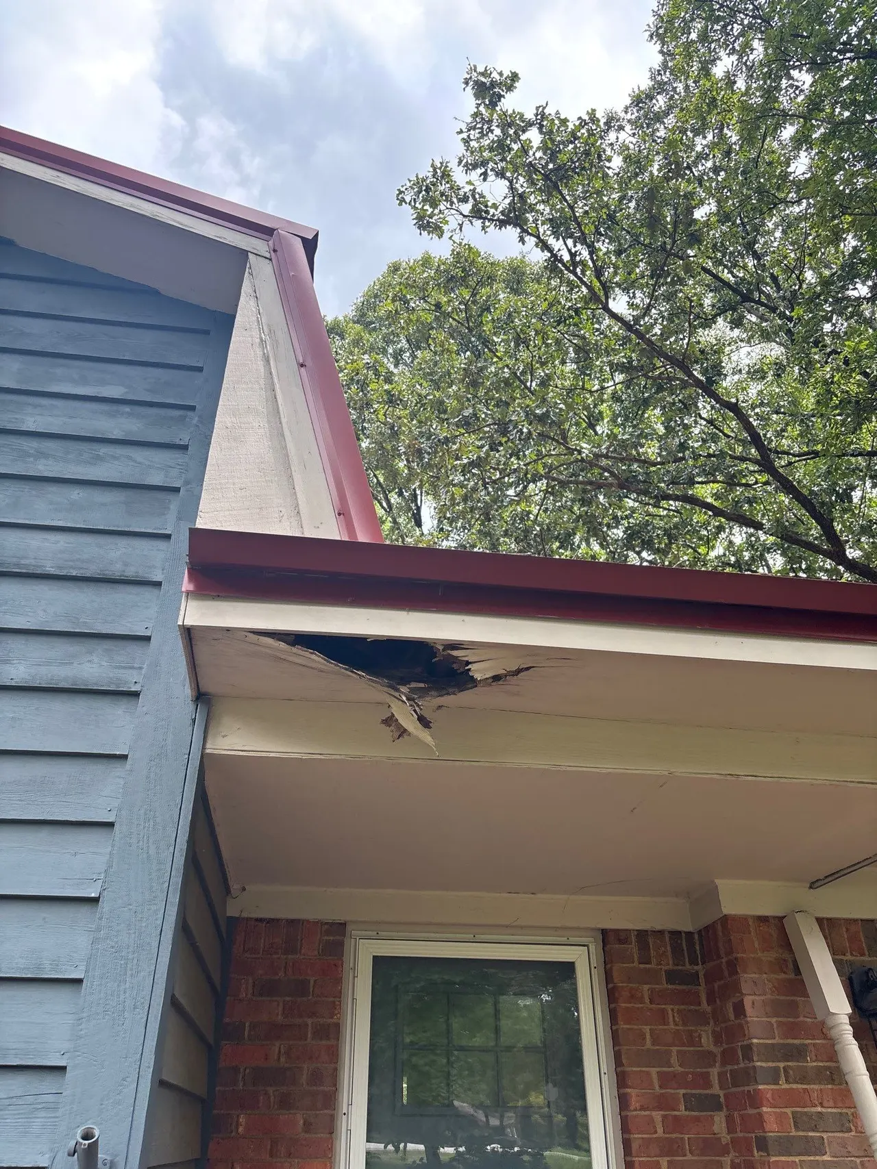 APS Foundation Repair and Waterproofing inspecting damaged soffit and wood rot caused by clogged gutters at a residential