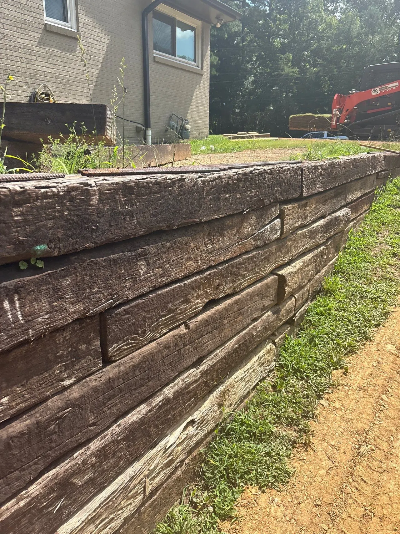 APS Foundation Repair and Waterproofing inspecting a bowing wooden retaining wall with decaying wood and exterior damage