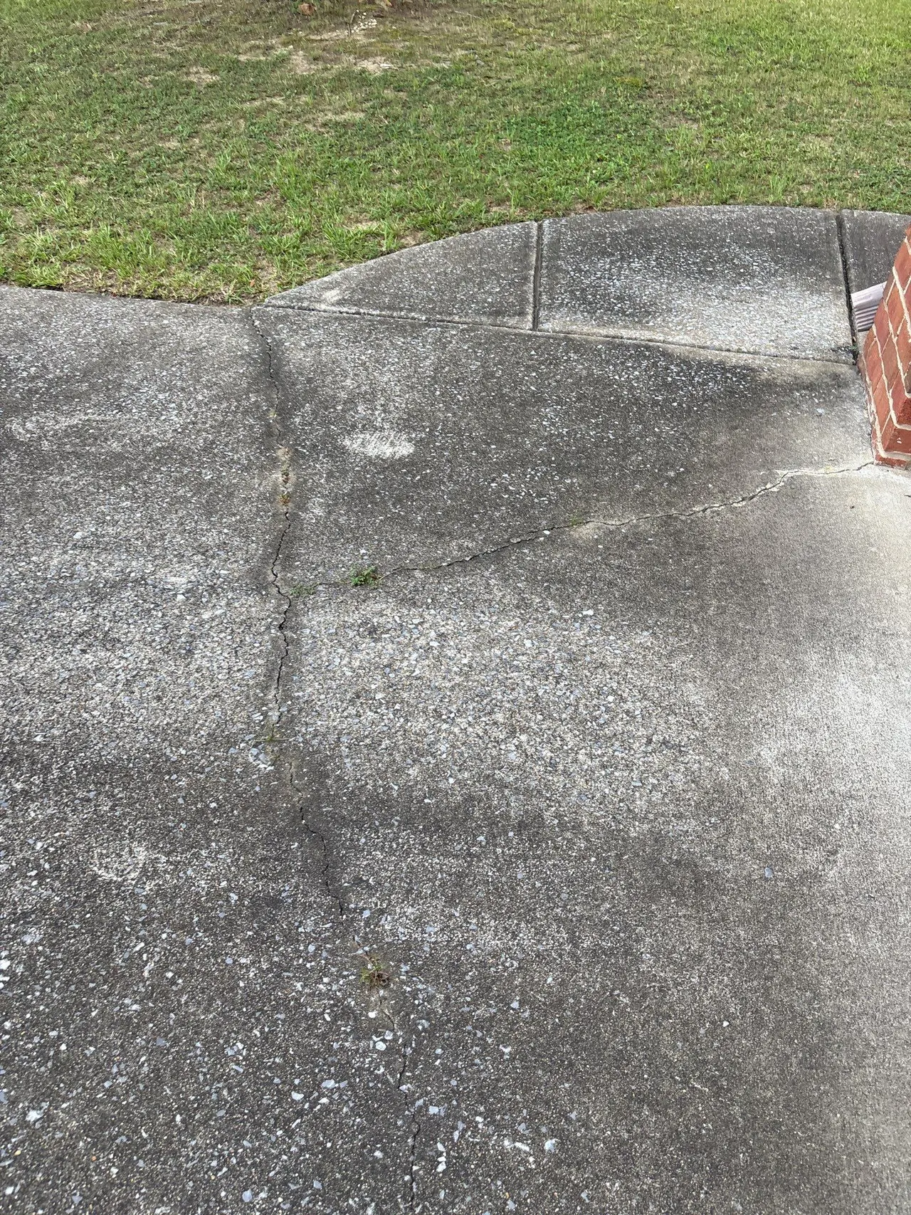 APS Foundation Repair and Waterproofing inspecting cracked concrete sidewalk with hairline fissures and surface cracks.