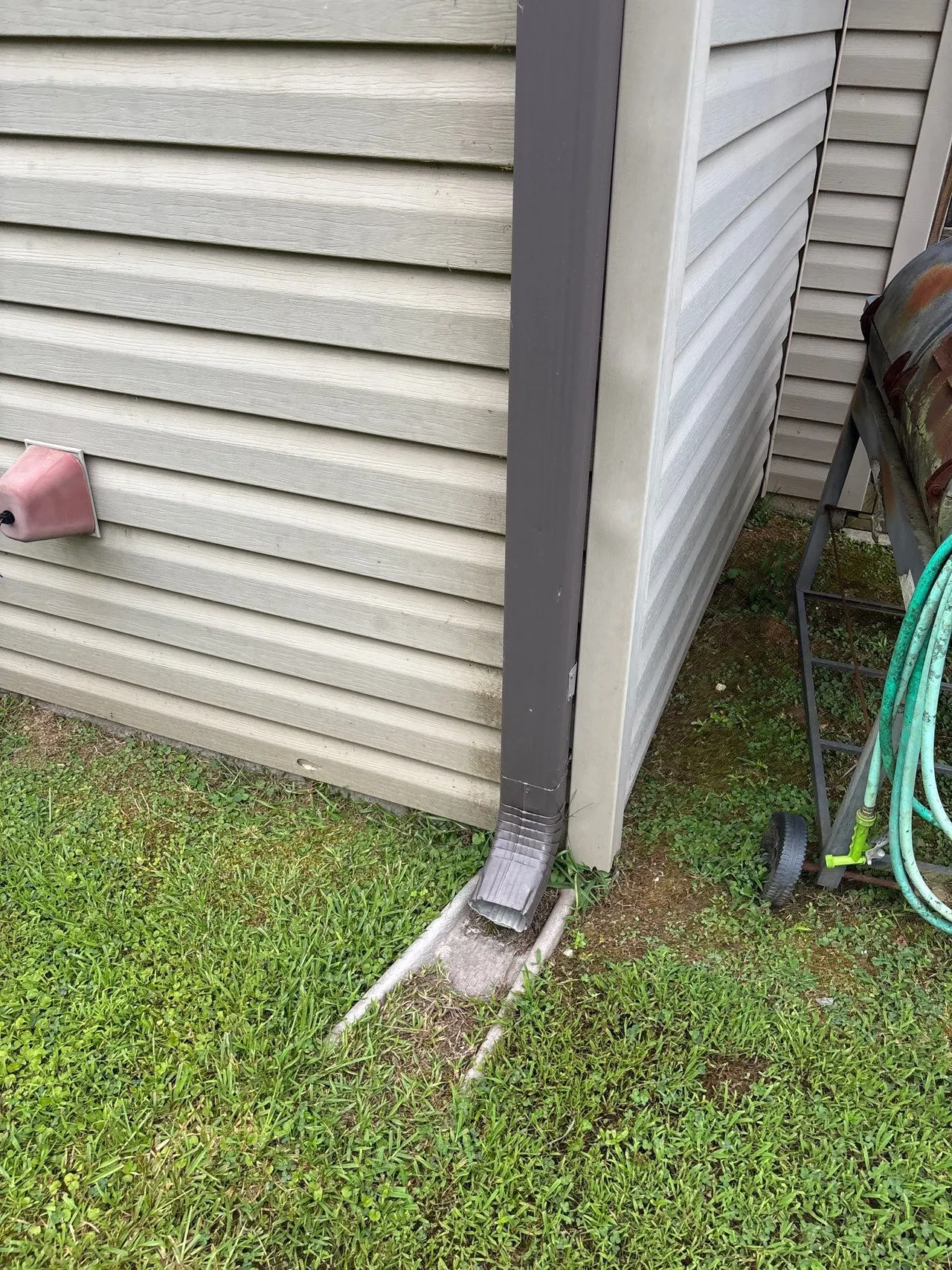 APS Foundation Repair and Waterproofing inspecting improper downspout discharge and water runoff near a home's foundation