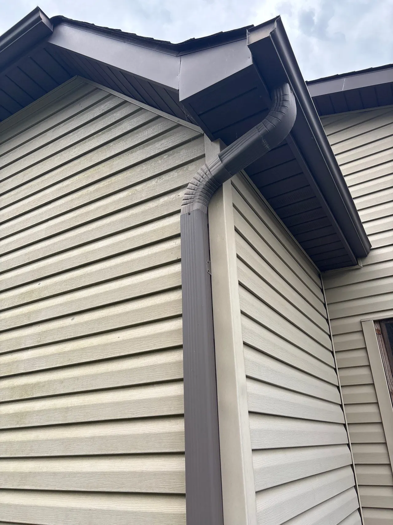 APS Foundation Repair and Waterproofing assessing water overflow from clogged gutters causing staining on siding