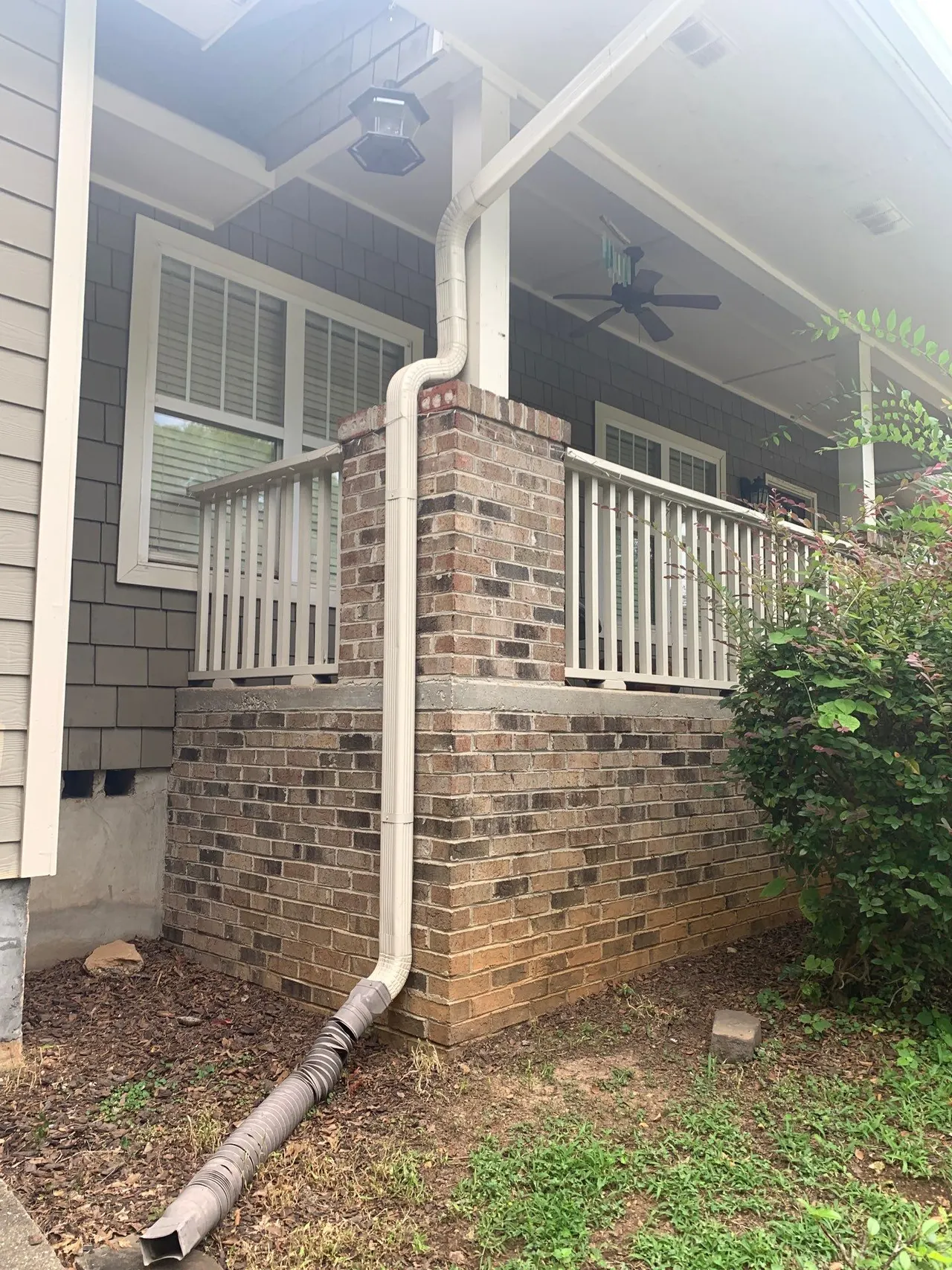 APS Foundation Repair and Waterproofing analyzing an exterior downspout and flexible drainage pipe at a residential home