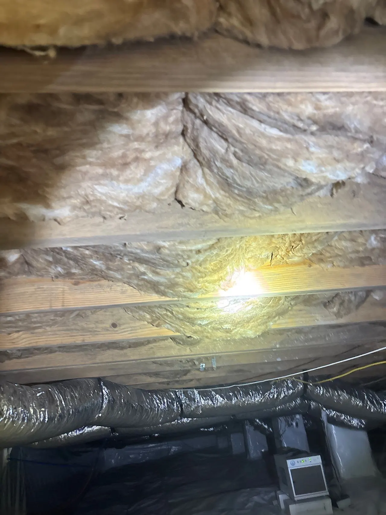 APS Foundation Repair and Waterproofing inspecting damp crawl space insulation with visible mold, next to a dehumidifier