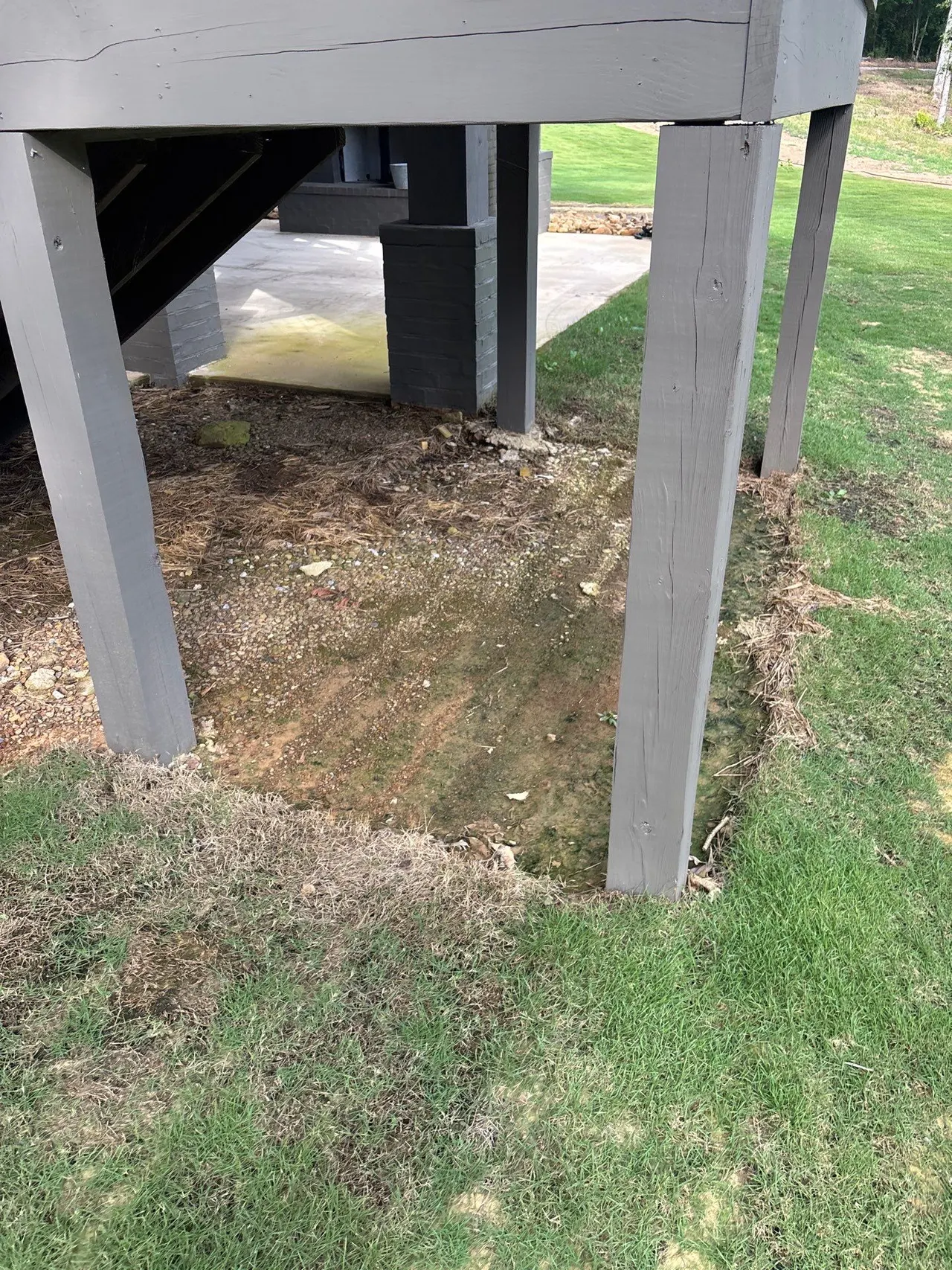 APS Foundation Repair and Waterproofing inspecting foundation water signs from standing water under a deck in Westover, AL.