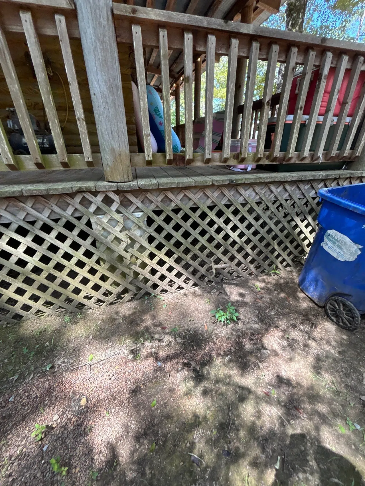 APS Foundation Repair and Waterproofing inspecting damaged wood lattice crawl space access well in Westover, AL.