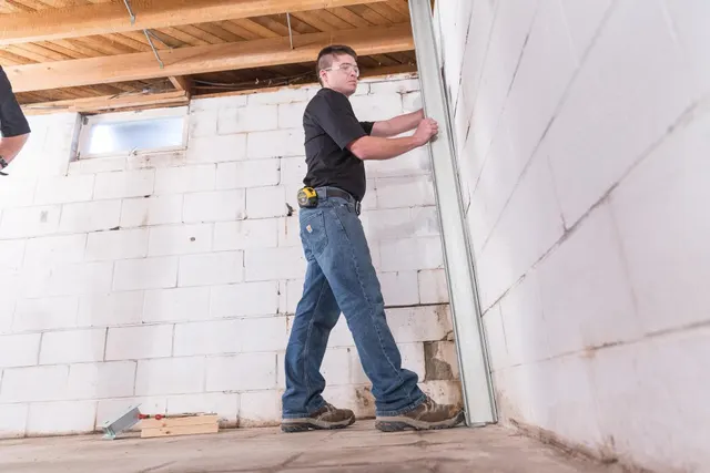APS Foundation Repair and Waterproofing technician installing structural reinforcement for a basement wall.