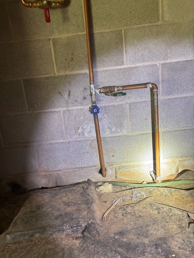 APS Foundation Repair and Waterproofing inspecting moisture on copper pipes and wall stains in a damp basement in Alabaster
