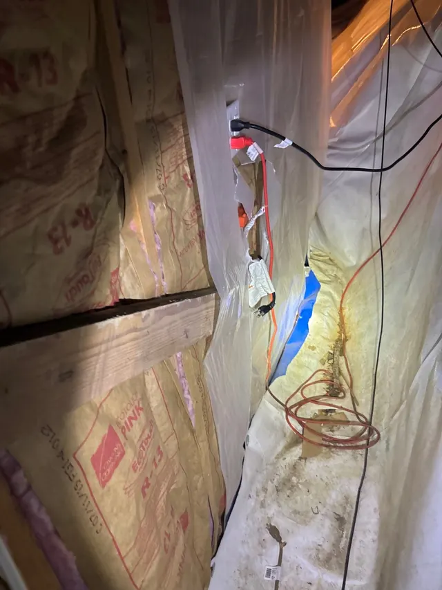 APS Foundation Repair and Waterproofing inspecting a damaged crawl space vapor barrier, moisture stains, and insulation